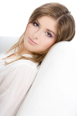 Obraz premium Portrait of a smiling beautiful young woman on sofa