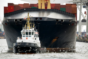tugboat towing freighter in harbor - obrazy, fototapety, plakaty