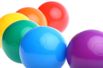Six shiny coloured plastic toy balls isolated on white
