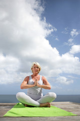 Fototapeta na wymiar Femme senior faisant du yoga sur un ponton