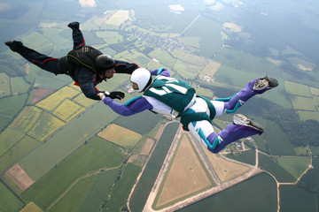 Two skydivers in freefall holding hands