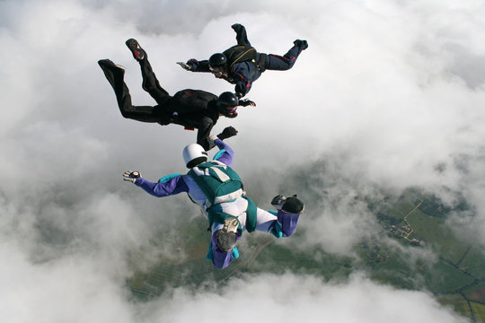 Three skydivers in freefall holding hands