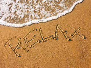 relax written in the sandy beach