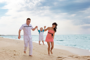 Fototapeta na wymiar Family running along the beach