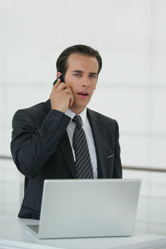 Homme en costume avec téléphone portable et ordinateur portable