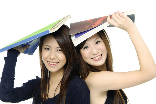 Pretty asian smiling and holding book on head