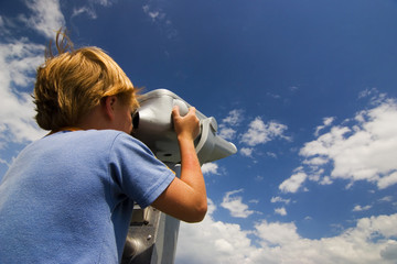 Boy look into metal binocular at beautiful sky
