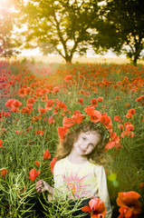 Obraz na płótnie Canvas Smiling little girl in the poppy field