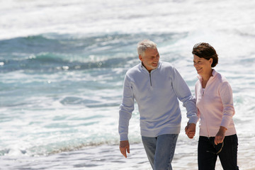 Couple de seniors souriants marchant au bord de la plage