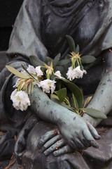 Grabstatue mit verwelkten Blumen