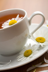 Obraz na płótnie Canvas white cup of herbal tea and camomile flowers