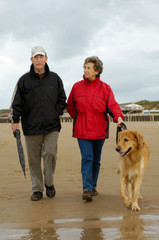 Seniorenpaar mit Hund beim Strandspaziergang