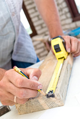 A woodworker measures the mark for his cut