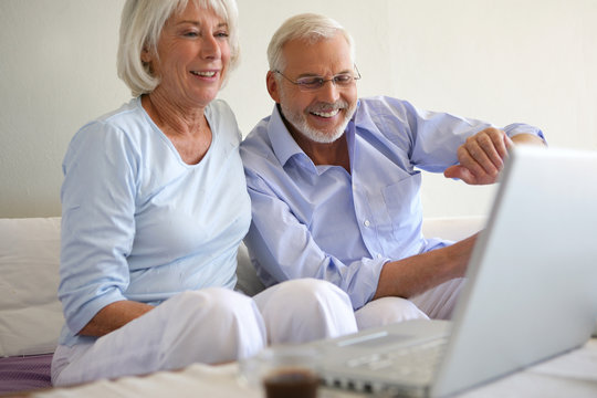 Couple de seniors souriants connectés à une webcam