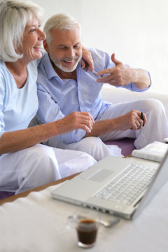 Couple de seniors souriants connectés à une webcam