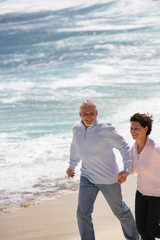 Couple de seniors souriants marchant au bord de la plage