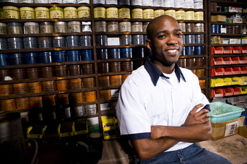 Man sitting in front of colored inks in print shop