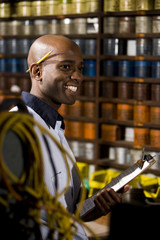Worker in print shop by shelves of ink