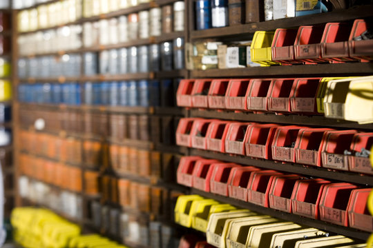 Side view of small red bins lined up on shelving