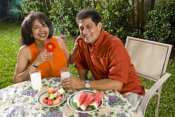 Mature interracial couple having refreshments in backyard