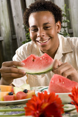 Teenage boy enjoying watermelon in back yard