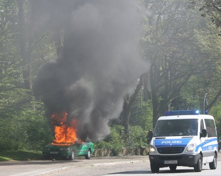 Brennendes Polizeiauto mit Mannschaftswagen