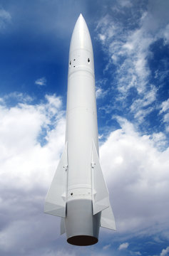 A White Rocket Against a Cloudy Blue Sky