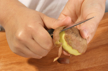 eine Kartoffel wird für  eine Kartoffelsuppe geschaelt