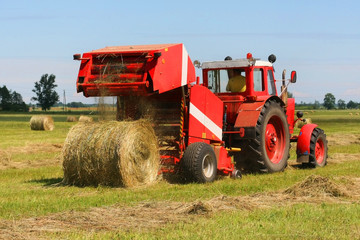 Red tractor working in the field (focus on a tractor)