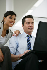 homme et femme souriants assis devant un ordinateur