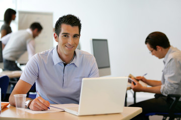 Jeune homme souriant en formation devant ordinateur