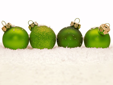 grüne weihnachtskugeln im schnee aufgereiht 