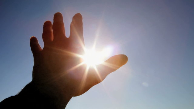 Hand in silhouette raised up to the sun
