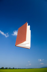 Book flying over a deep blue sky