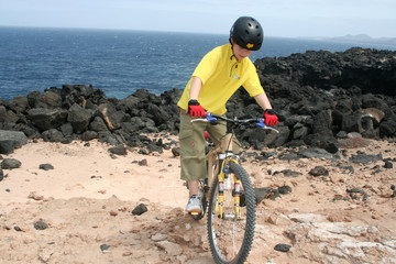 Kind fährt mit Mountainbike im Gelände die Küste entlang