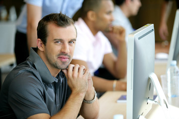 Portrait d'un homme souriant au bureau devant un ordinateur