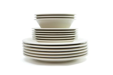 Stack of beige dinner plates, soup plates and saucers isolated
