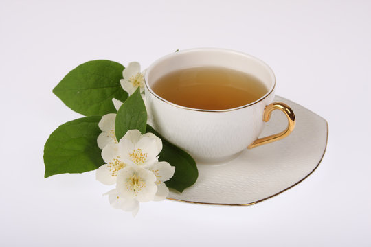 White cup of tea with jasmine flowers isolated on white