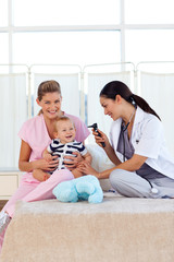 Baby playing with pediatrician and nurse