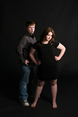 teenage couple standing together against dark background