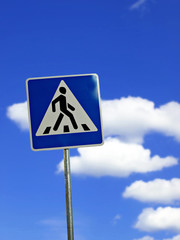 blue crosswalk sign on cloudy sky background