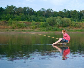 girl-fisher sits on a log in the middle of the river - 15359382