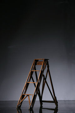 Holzleiter im Studio vor grauem Hintergrund