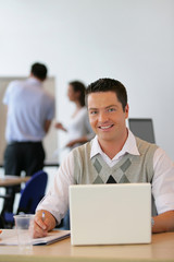 Homme souriant au bureau devant un ordinateur