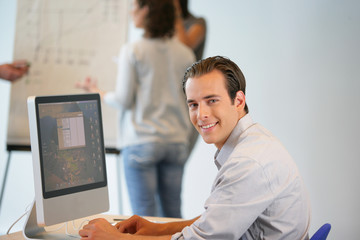 Portrait d'un homme souriant au bureau devant un ordinateur