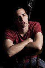 Young man smoking cigar, isolated on black