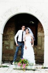 Bride and groom standing under white arch with flowers