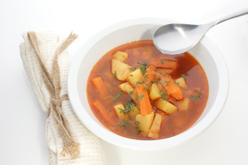 Kartoffelsuppe in einer weissen Schale mit einem Löffel