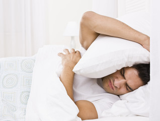 Fototapeta na wymiar Tired Man Hiding His Head with Pillow