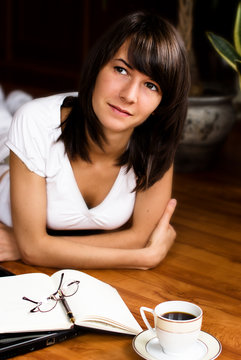Young woman lying on the floor with a notebook and coffee